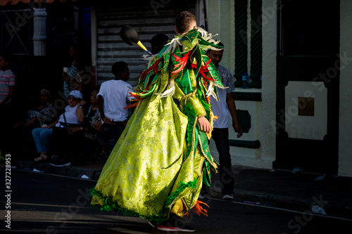 young man in colorful costume pass by on city street at traditional dominican carnival © alkiona_25