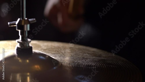 Hands of musician holds drum sticks hits on crash cymbal on dark background