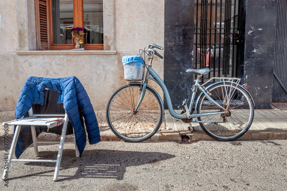 Bicycle parked on the street next to a plastic chair on a sunny morning. Sport and loneliness