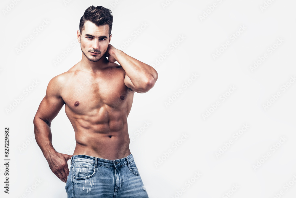 Male shirtless model with perfect body in jeans posing over white background. Close-up. Studio shot. Male shirtless model with perfect body in jeans posing over white background. Close-up. Studio shot.