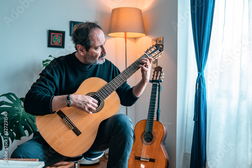 Seniors man are playing a guitar at home. Retired man learning playing a guitar.