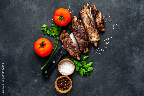 grilled pork ribs over meat knife with spices on a stone background
