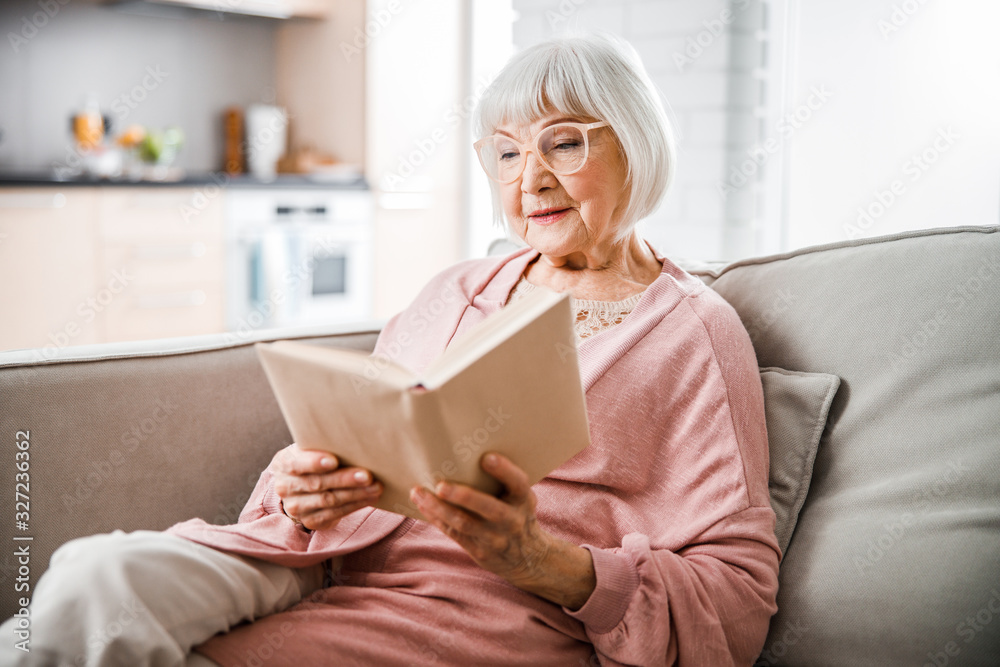 © Yakobchuk Olena - Senior woman in glasses reading book at home