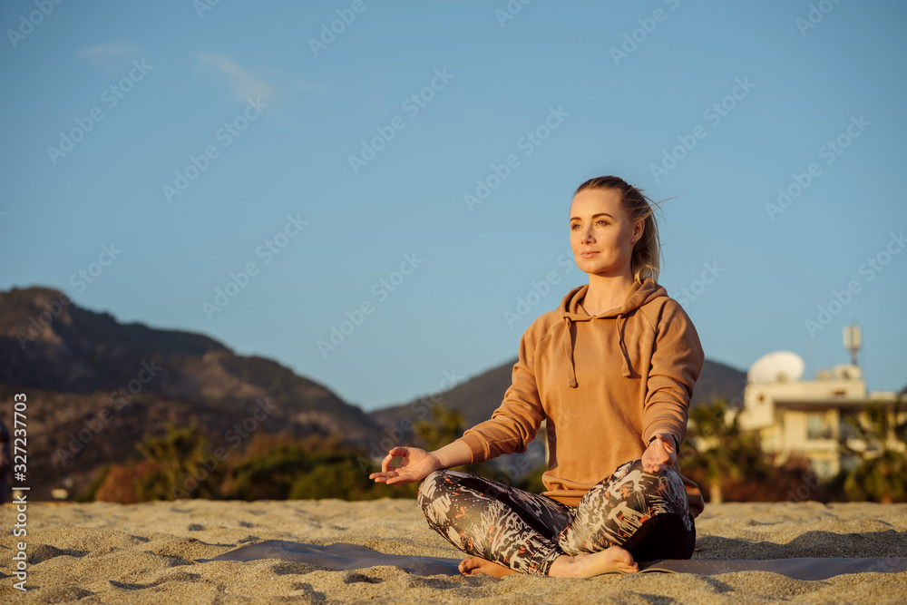 woman doing yoga on the beach barefoot front view blue sky and mountains on background; yoga and health concept. woman doing yoga on the beach barefoot front view blue sky and mountains on background; yoga and health concept.
