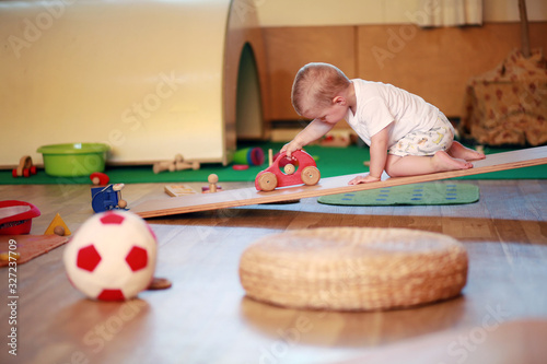 Little boy playing independently in a playgroup with red  toy car