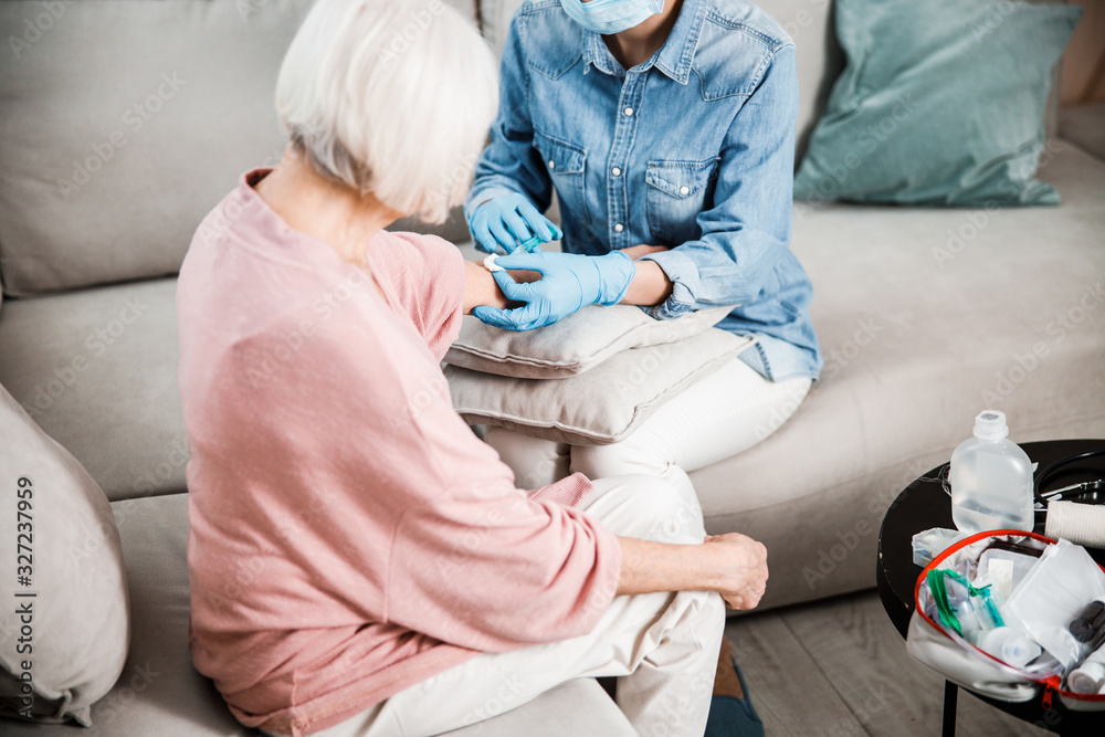 Obraz premium Female doctor making injection to old woman arm
