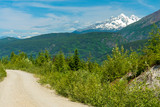 Snowy mountains tower over a dirt road near Usk, British Columbia, Canada