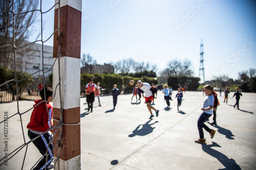 unrecognizable young boys and girls playing soccer in the schoolyard