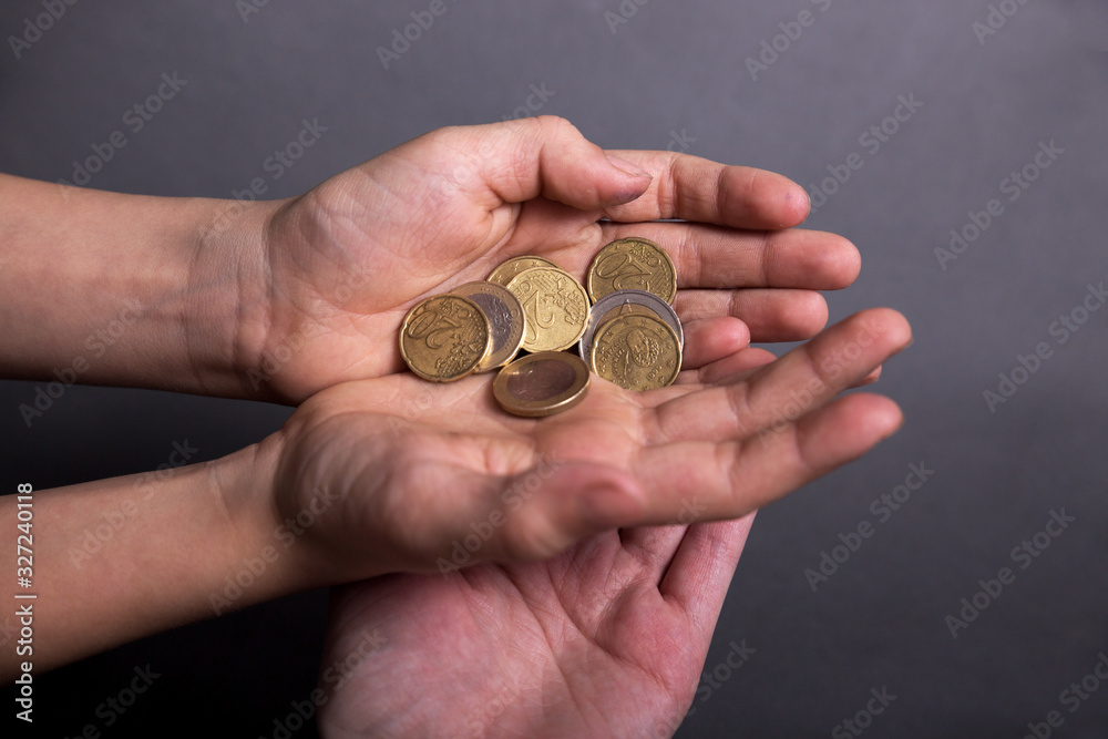 child with adult hold in his little hands money euro on grey background child with adult hold in his little hands money euro on grey background