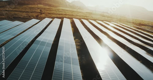 Aerial view looking down on rows of blue solar panels at sunrise, the future of green renewable energy is the solar farm