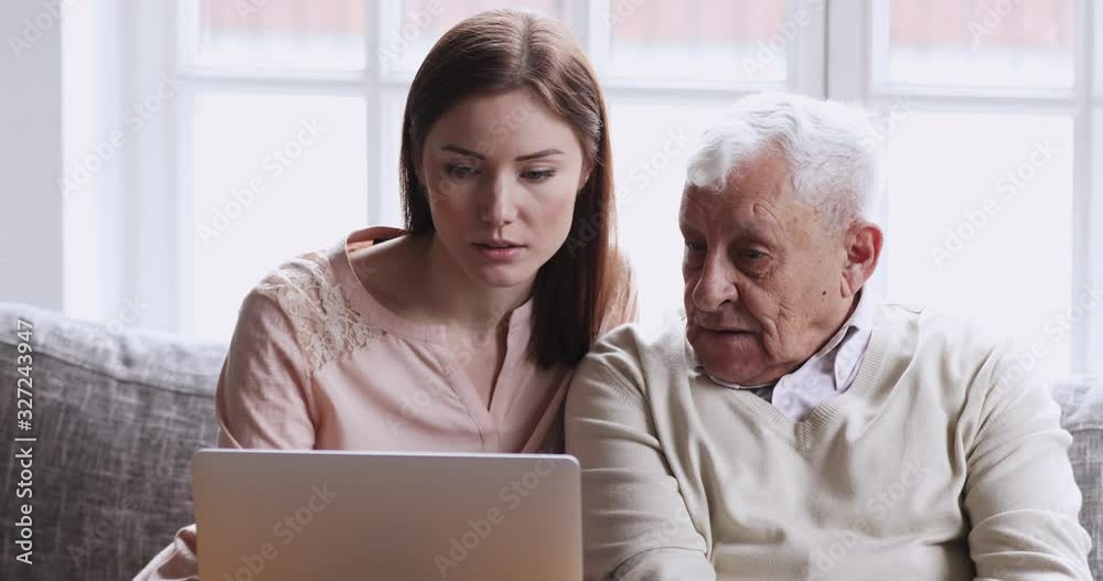 Young granddaughter teaching senior grandad learning using laptop computer Young granddaughter teaching senior grandad learning using laptop computer