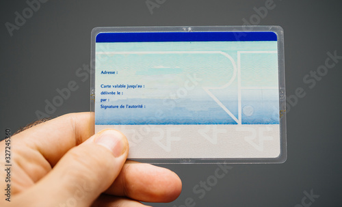 Paris, France - Mar 31, 2019: Man hand holding against gray background the rear part of National identity card Carte nationale d identite photo