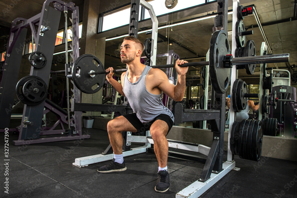 young man working out in gym doing exercises with barbell. young man working out in gym doing exercises with barbell.