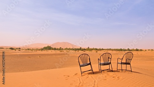 Three chairs left on the sand dunes in Sahara Desert , Morocco