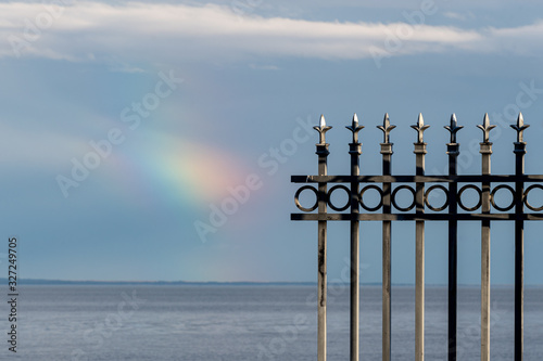 Decorative Metal Fence Against the Sky and Water After the Rainstorm with Rainbow