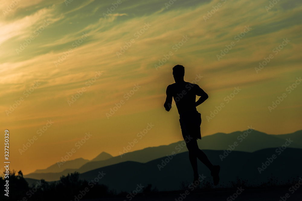 Male silhouette running in mountains under sunlight
