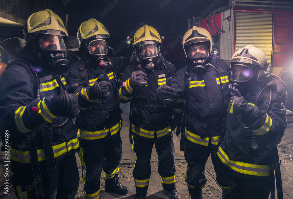 Team of firemen in uniform with gas masks inside the fire department Team of firemen in uniform with gas masks inside the fire department