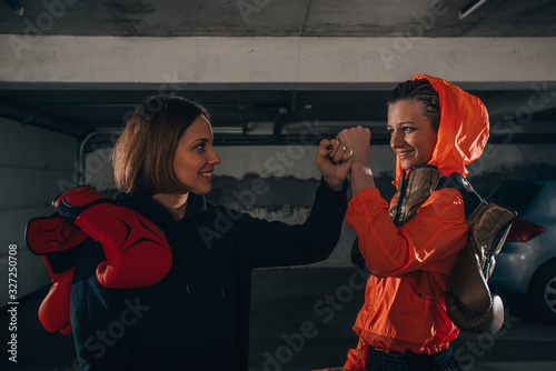 Profile pricture of two happy women boxer friends smiling and making high five before workout photo