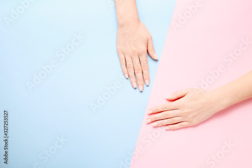 Stylish trendy female manicure. Beautiful young woman s hands on pink and blue background.