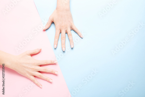 Stylish trendy female manicure. Beautiful young woman s hands on pink and blue background.