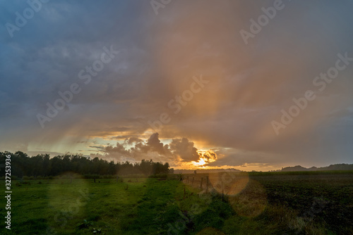 scenic dramatic sunset sky background over a field in the region "Goldenstedter Moor" near Vechta (Lower Saxony, Germany) with light reflecting in raindrops
