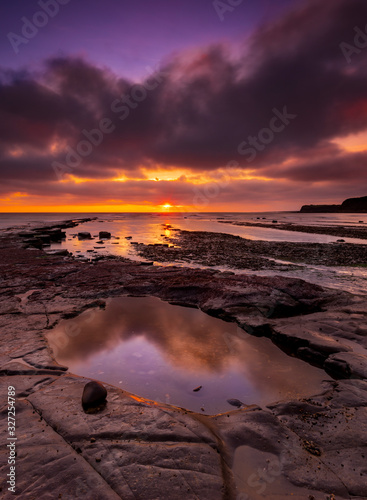 The sky clears after a rain storm just long enough to show the deep red and purple clouds over the South Dorset jurassic coastline