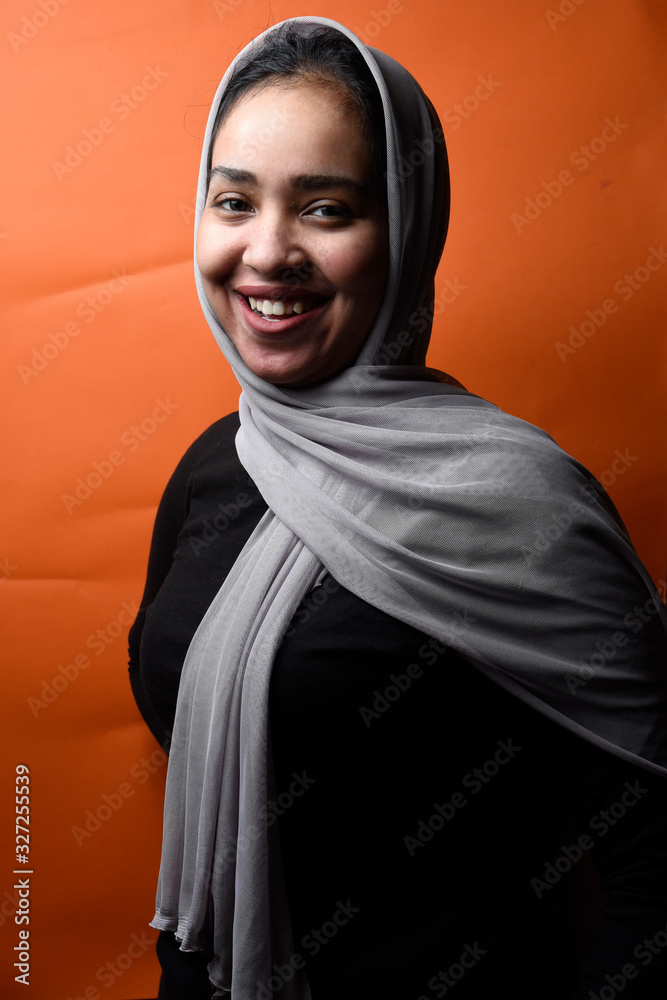 Portrait of happy Arabic girl wearing Hijab on orange background,beautiful Middle Eastern girl in Arabic Traditional Abbaya Portrait of happy Arabic girl wearing Hijab on orange background,beautiful Middle Eastern girl in Arabic Traditional Abbaya