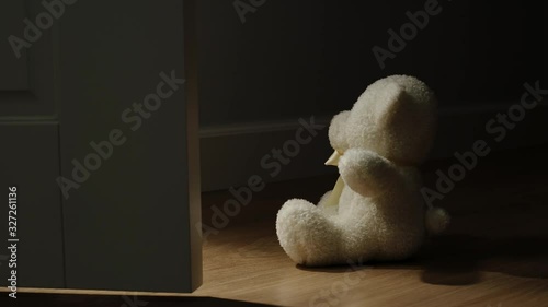 Door Opening In Front Of Plush Bear Toy Sitting On The Floor In A Dark Room