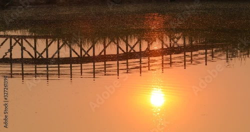 The reflection of the old bridge on the river,The silhouette of the old wooden bridge at sunrise or sunset in the countryside photo