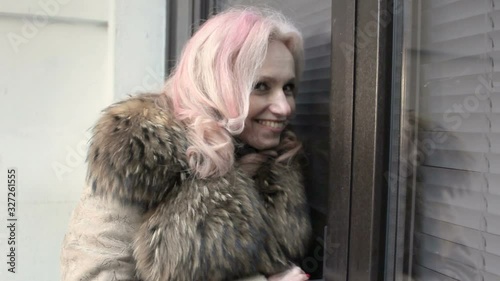 Adult woman with white-pink hair, looking out the window photo