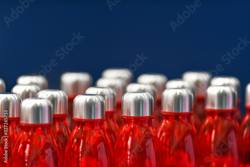 Red water bottles with silver metallic caps in rows isolated on blue background photo