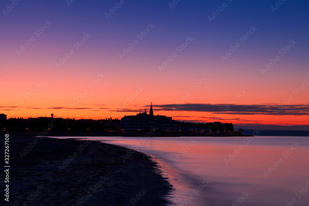 Alba sulla città di Grado vista dalla laguna. Provincia di Gorizia, Friuli Venezia Giulia, Italia, con cielo e mare colorato.