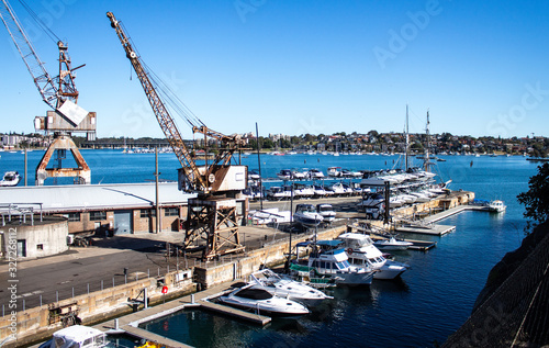 Dockyard wharf working shipyard on harbour with cranes, boats, clear blue sky © squirrel7707