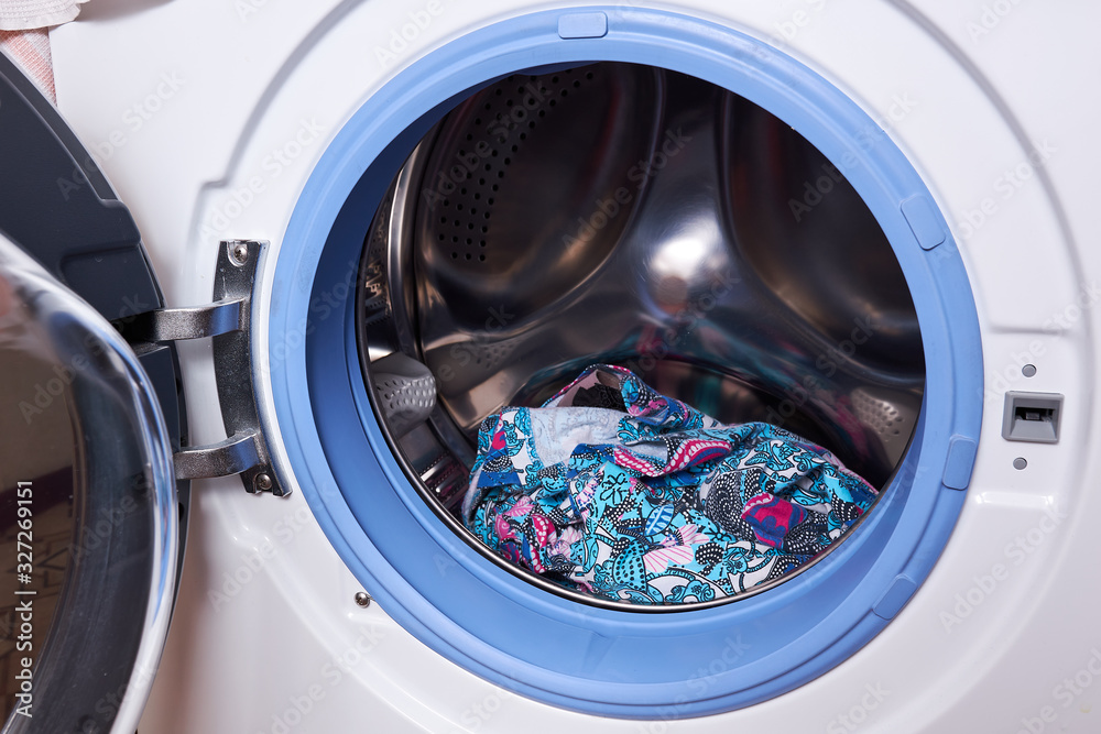 Wet washed laundry in washing machine with the door open, closeup. washing machine loaded with colorful bright towels and laundry Wet washed laundry in washing machine with the door open, closeup. washing machine loaded with colorful bright towels and laundry