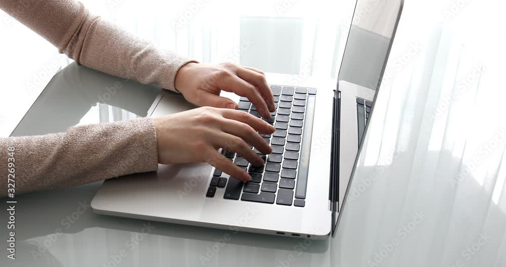 Woman behind laptop in office printing text on keyboard Woman behind laptop in office printing text on keyboard