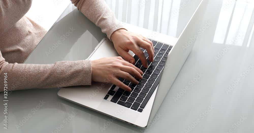 Woman behind laptop in office printing text on keyboard Woman behind laptop in office printing text on keyboard