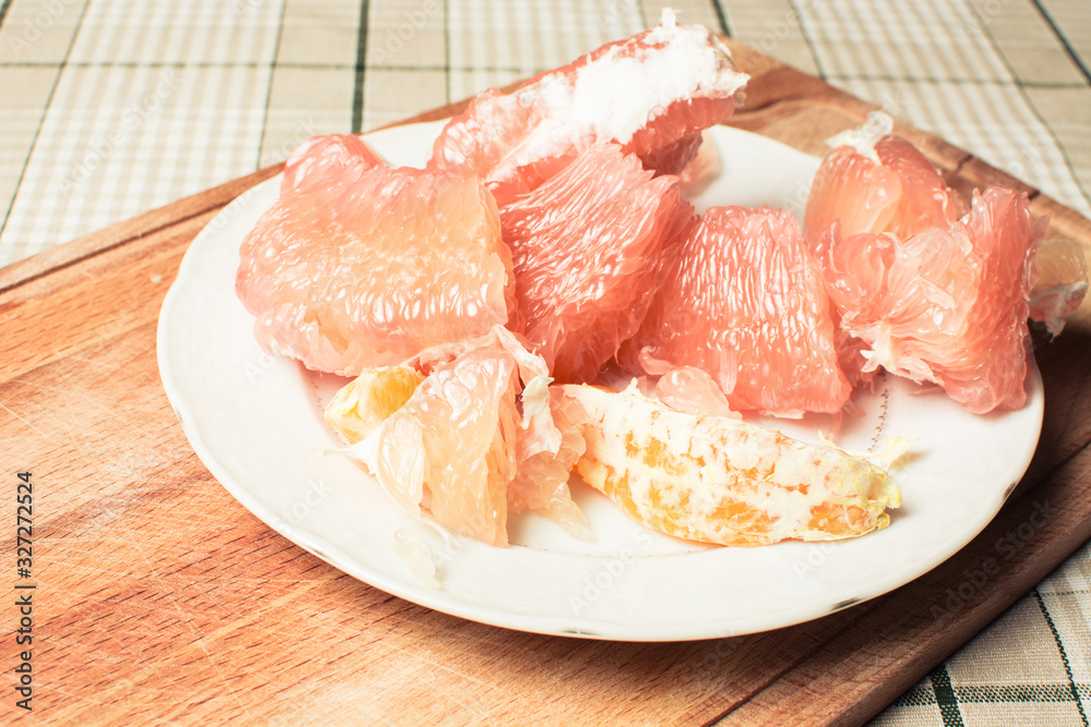 Cut pamela fruit in plate on wooden board.