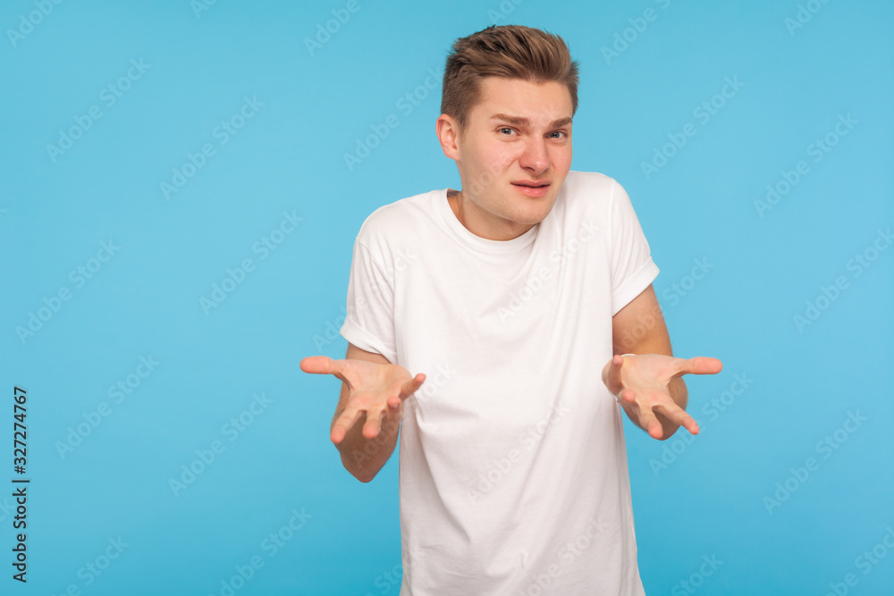 What do you want? Portrait of confused man in t-shirt expressing misunderstanding, gesturing in puzzlement with indignant face, asking why'd you do that. indoor studio shot isolated on blue background What do you want? Portrait of confused man in t-shirt expressing misunderstanding, gesturing in puzzlement with indignant face, asking why'd you do that. indoor studio shot isolated on blue background