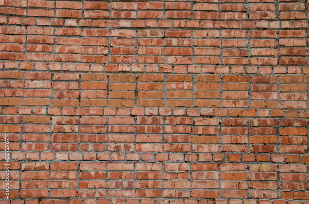 Fototapeta premium Abstract background. An old texture, an UN-plastered wall of red brick with streaks of gray crumbled cement. Background, structure.
