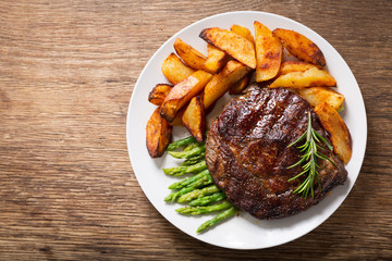 plate of grilled steak with rosemary, asparagus and potato, top view