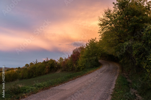 A mountain road below orange coloured clouds at sunset