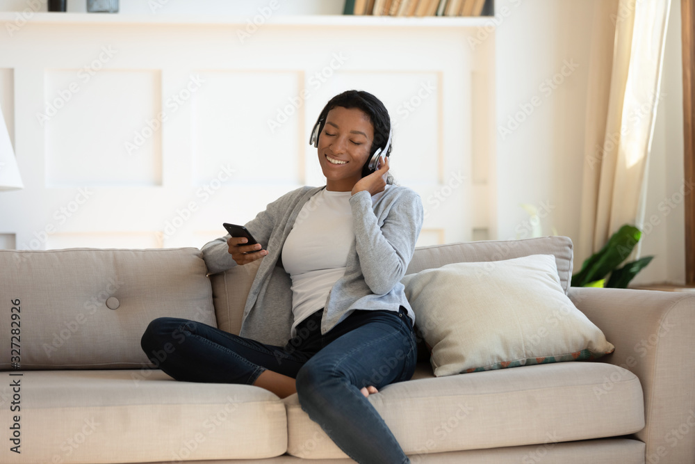 Obraz premium African American woman in headphones using smartphone gadget