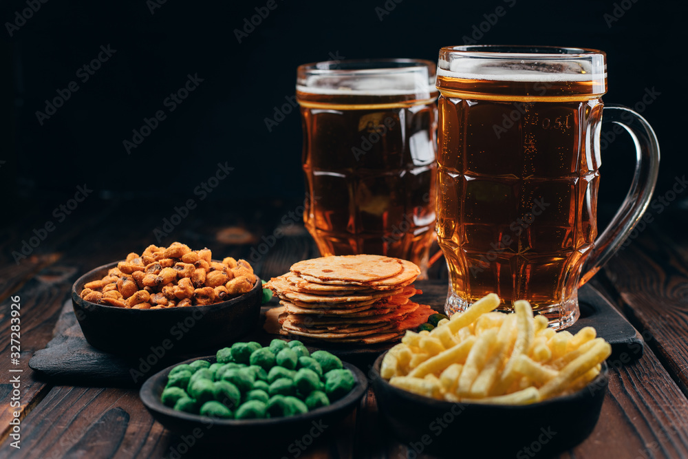 Beer and appetizing snacks. table with two mugs of craft lager and salty traditional appetizers. Finger food. Oktoberfest food, pub concept Beer and appetizing snacks. table with two mugs of craft lager and salty traditional appetizers. Finger food. Oktoberfest food, pub concept