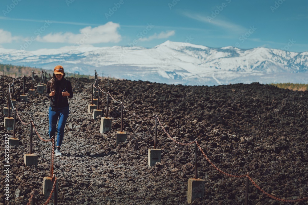 Asian woman travelers walk on the ground caused by volcanic ash with snow mountian background.Hiking and adventure travel concept.