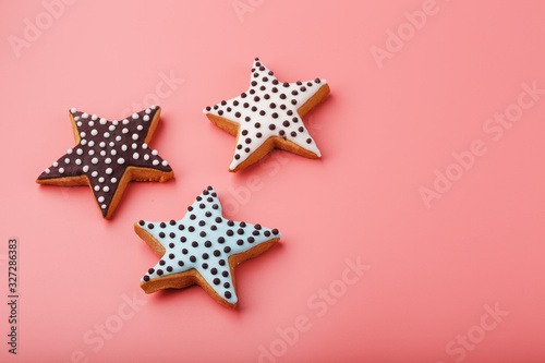 A close-up of three homemade glazed gingerbread cookies is made in the form of stars on a pink background. Handmade cookies.