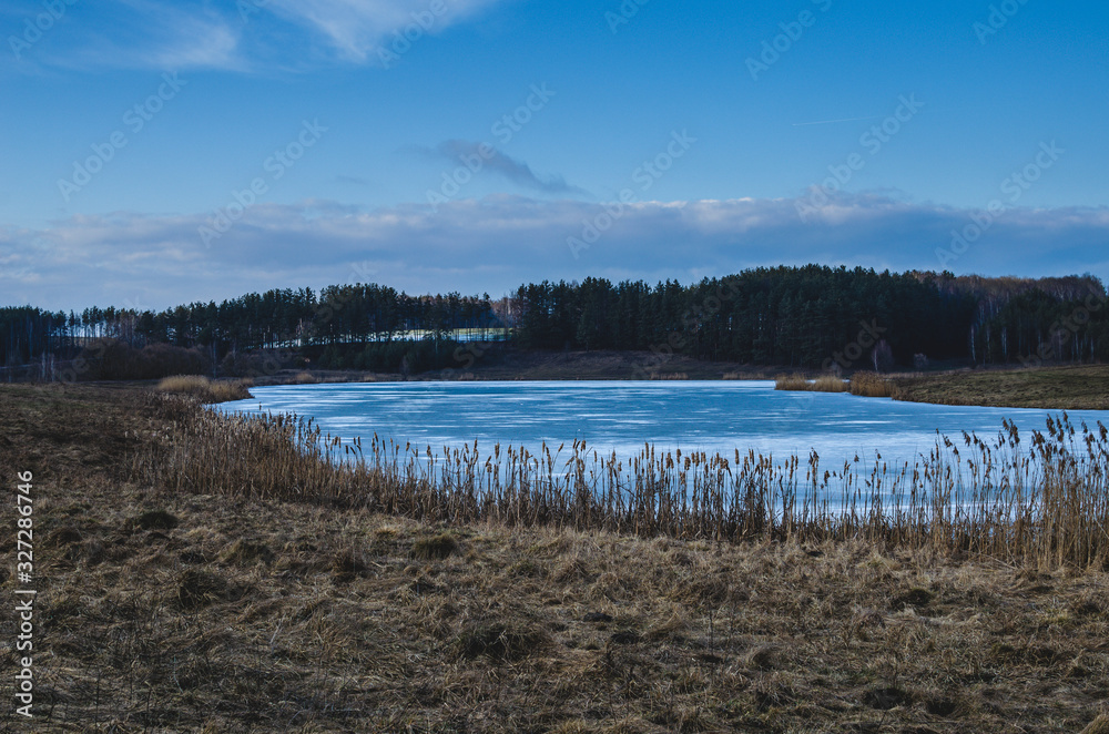 Frozen lake in the spring in the evening. Cloudy weather on the lake in early spring. Lake landscape in early spring