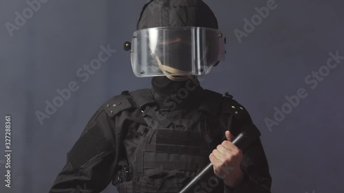 special forces soldier threatens crowd of protesters with baton or stick, police officer stands in cordon ready to engage in clashes with rebels or resistance