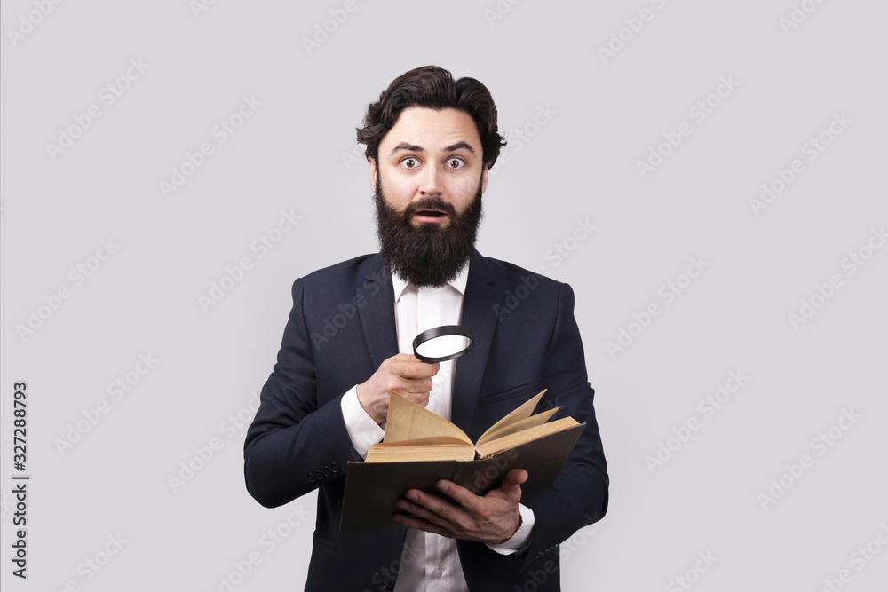 shocked bearded man reading book with magnifier, male over gray background shocked bearded man reading book with magnifier, male over gray background
