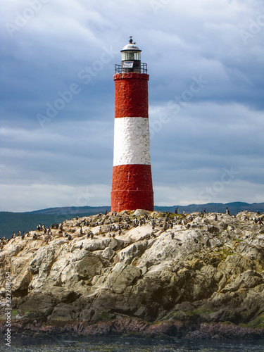 Red and white striped lighthouse on rocks