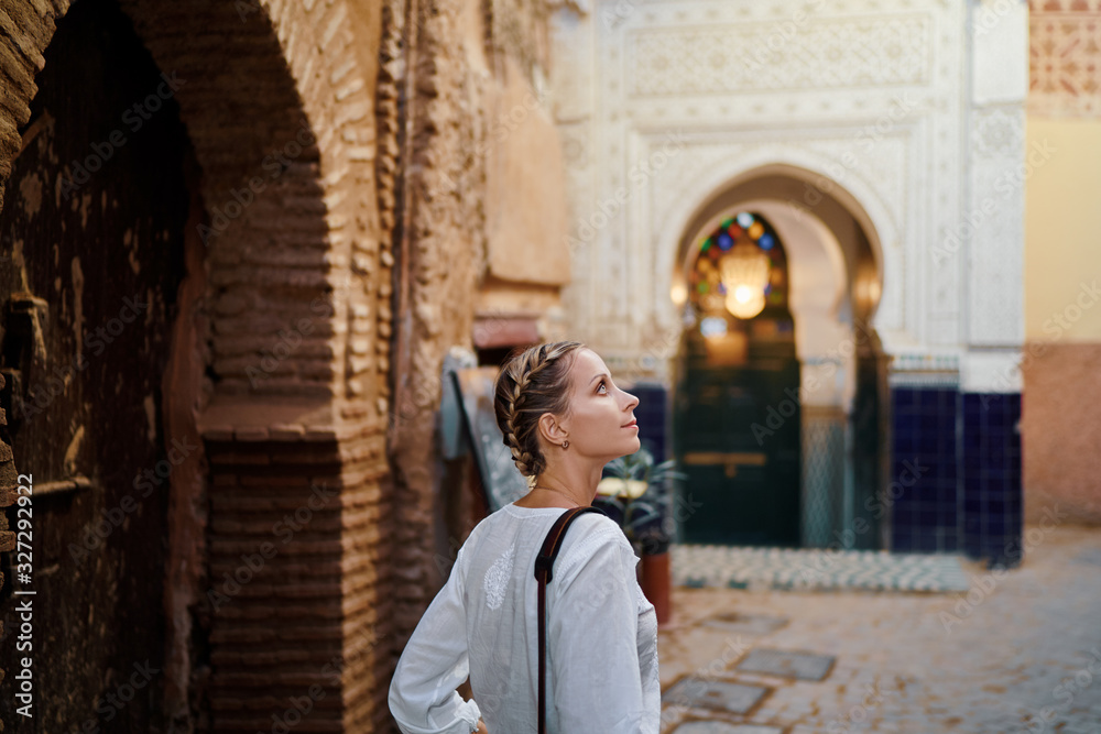 Travel and active lifestyle concept. Young traveller woman walking in ancient moroccan town.